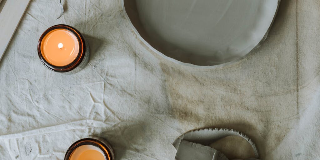 An overhead view of a workspace with various clay pieces arranged in a circular pattern, each piece labeled with a different price point. The workspace is filled with tools and materials, creating a vibrant and creative atmosphere.