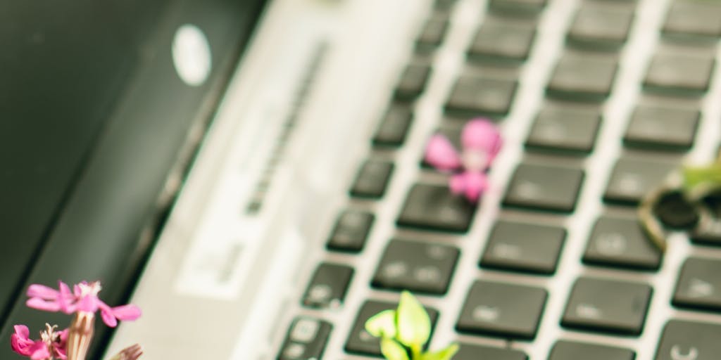 A close-up of a hand typing on a laptop keyboard with the Jasper AI interface visible on the screen, while a light bulb icon hovers above, symbolizing inspiration and innovative ideas generated by the AI.
