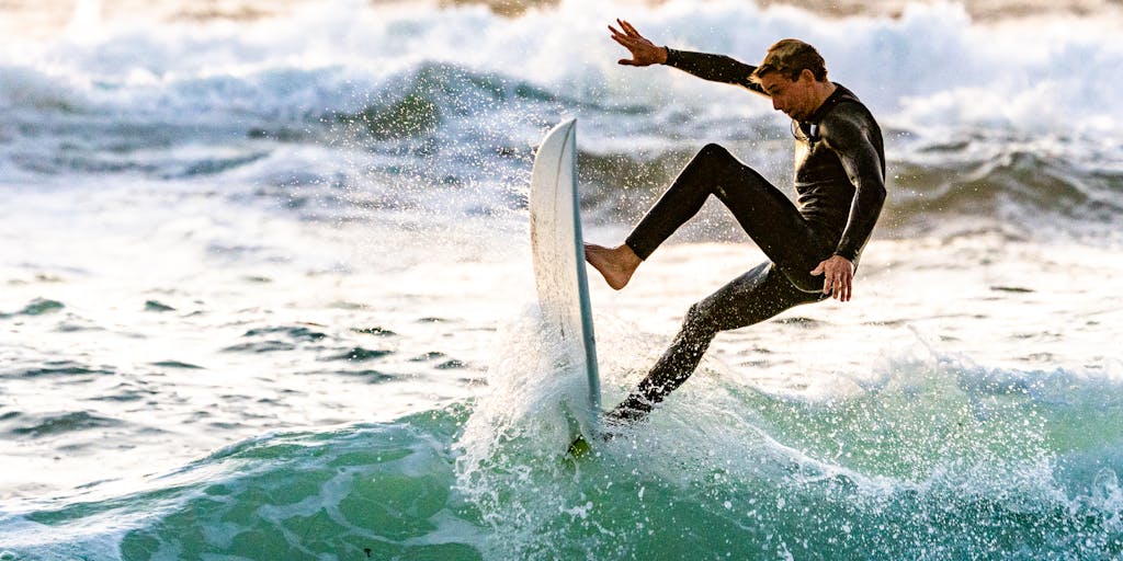 A dynamic shot of a surfer performing a trick on a wave, with a split-screen effect showing a laptop screen displaying a website's SEO performance metrics. This juxtaposition highlights the thrill of surfing alongside the excitement of achieving online visibility.