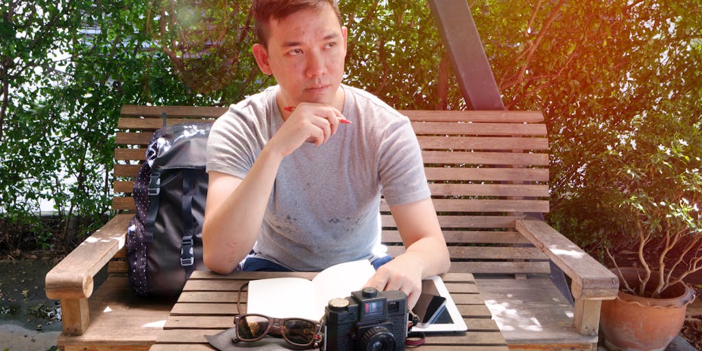 A person sitting in a park, using a tablet to access Seowriting.ai, surrounded by nature. The sunlight filters through the trees, creating a serene and inspiring atmosphere for writing. The focus is on the tablet screen, showcasing the app in action.