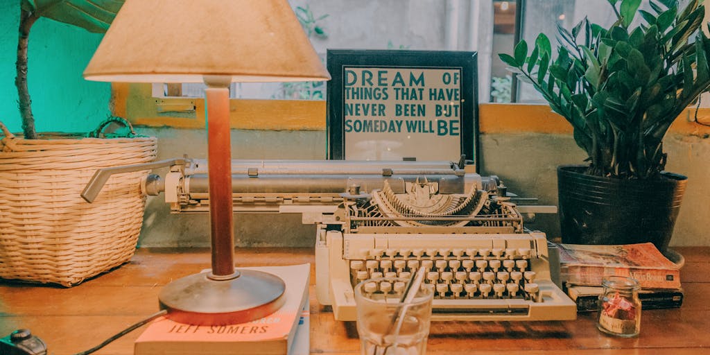 A cozy workspace featuring a vintage typewriter surrounded by modern technology, such as a laptop and tablet. The scene is illuminated by warm, natural light coming through a window, with a steaming cup of coffee on the desk. This juxtaposition symbolizes the blend of traditional and modern writing tools, representing alternatives to Zimmwriter.