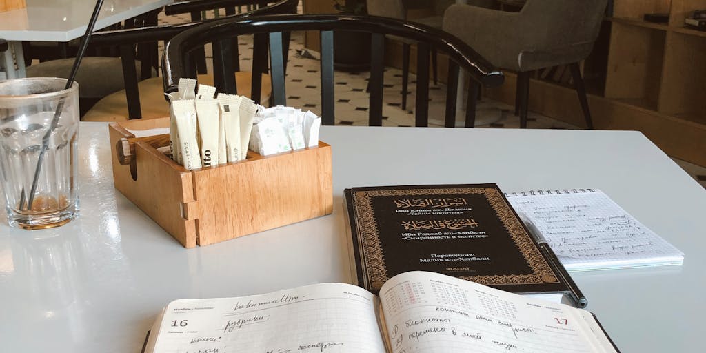 An overhead shot of a cozy workspace featuring a laptop with a 'Wordtune Alternative' interface open, surrounded by coffee cups, books, and a notepad filled with scribbles. The warm lighting creates an inviting atmosphere, emphasizing creativity and productivity.