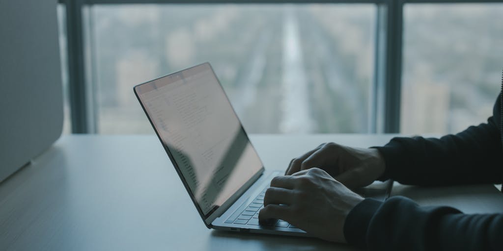 A close-up shot of a person’s hands typing on a laptop with the Ryte Alternative interface visible on the screen. The background features a blurred cityscape, symbolizing the connection between digital marketing and the fast-paced business world, highlighting the importance of effective SEO tools.