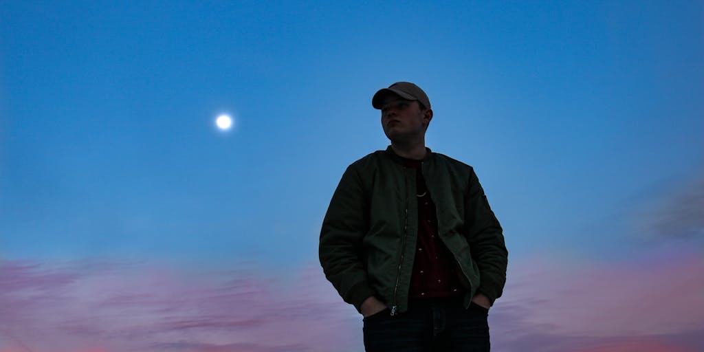 A person standing on a cliff at sunset, arms outstretched, with a large canvas behind them displaying an inspiring alternative phrase. The dramatic sky and the person's silhouette create a powerful visual representation of freedom and expression.