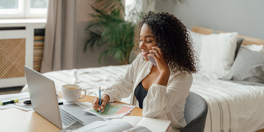 An overhead view of a cozy writing nook featuring a laptop, a steaming cup of coffee, and an open notebook filled with handwritten notes. The scene is softly lit by natural light coming through a window, creating a warm and inviting atmosphere for alternative writing methods.
