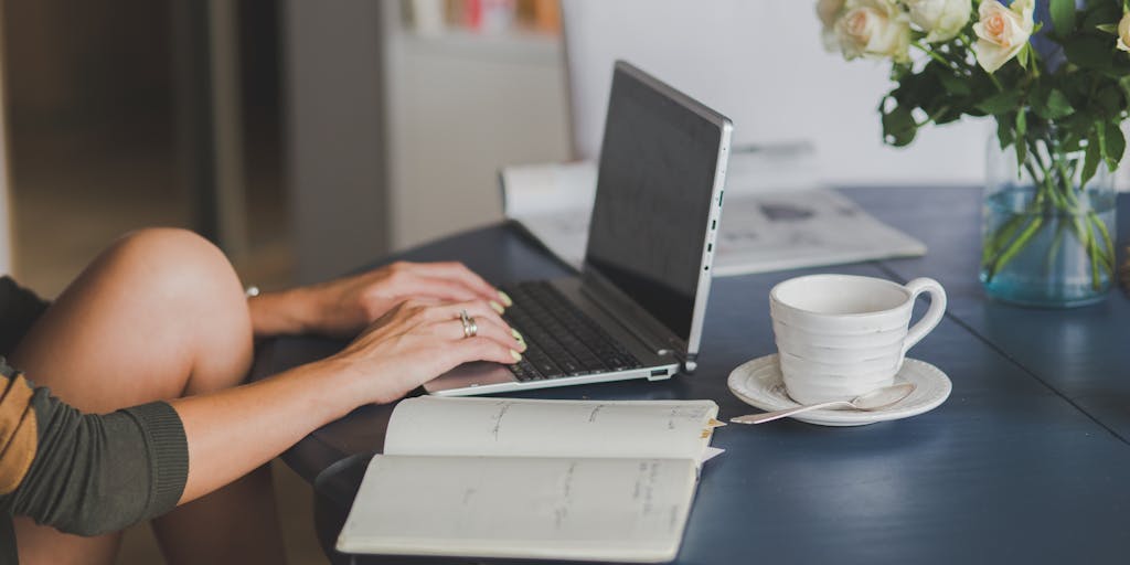 A split-screen image showing a person using a traditional pen and paper on one side, and on the other side, the same person using a laptop with a free AI writing tool open. The contrast highlights the transition from manual writing to digital assistance.