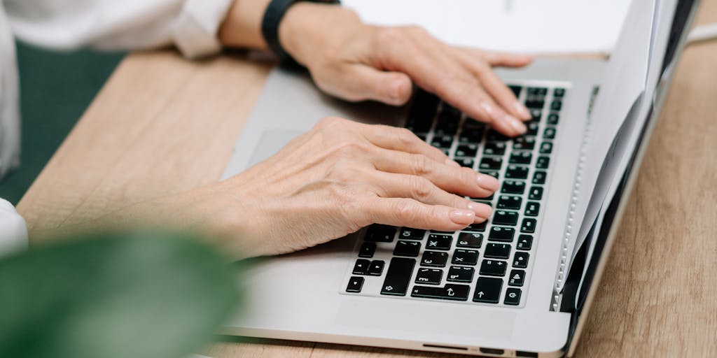 A close-up shot of hands typing on a keyboard with a screen in the background displaying a comparison chart of Wordai and its free alternatives. The image should capture the intensity of focus and the excitement of discovering new tools for writing.