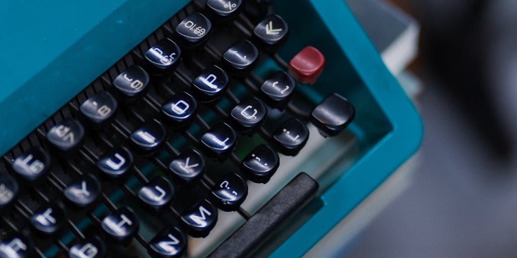A whimsical illustration of a robot sitting at a typewriter, surrounded by floating paragraphs of text. The robot has a friendly expression, and the scene is filled with colorful paper and ink splashes, representing the creative process of writing.