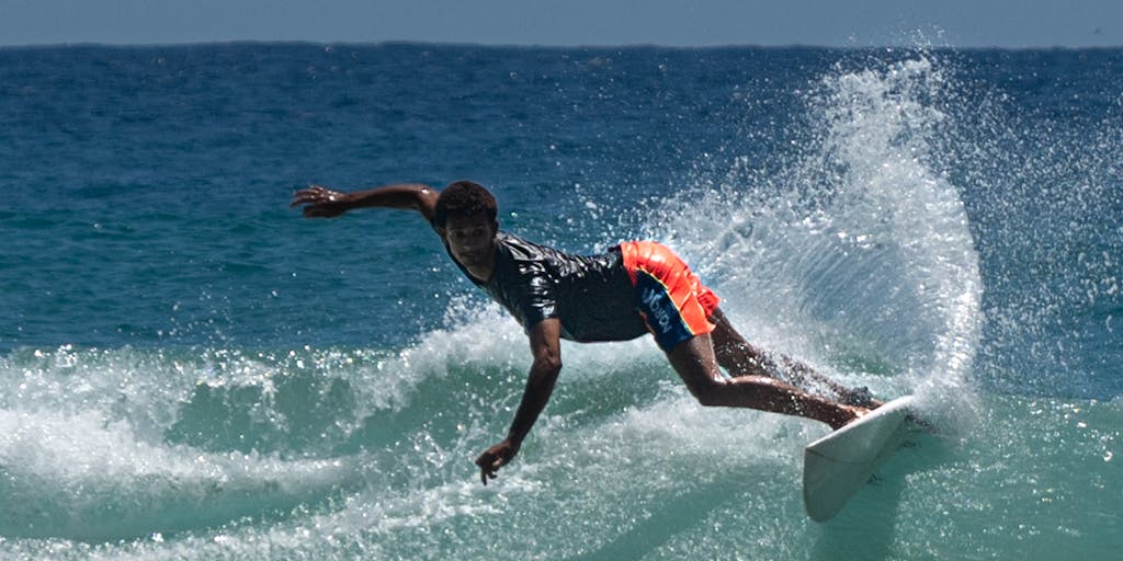 An action shot of a surfer catching a wave, with a digital overlay of SEO metrics and analytics appearing in the sky above the ocean. This visual metaphor represents the idea of riding the wave of SEO trends.