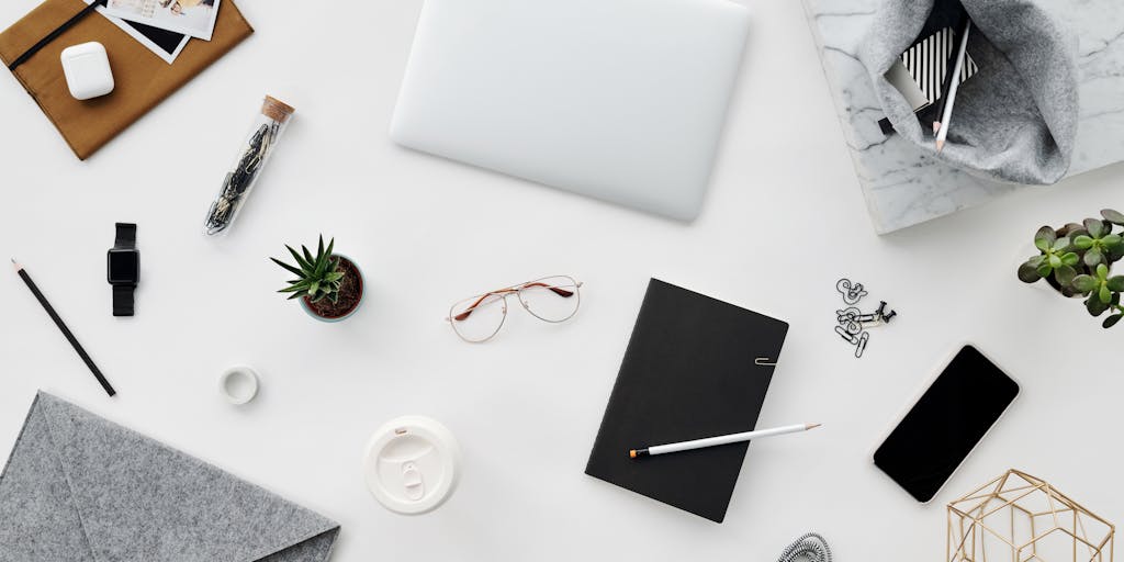 An overhead view of a workspace featuring a notebook with handwritten notes about Publer's features, a smartphone displaying the Publer app, and a plant for a touch of greenery. The scene is well-lit, creating an inviting atmosphere for content creators.