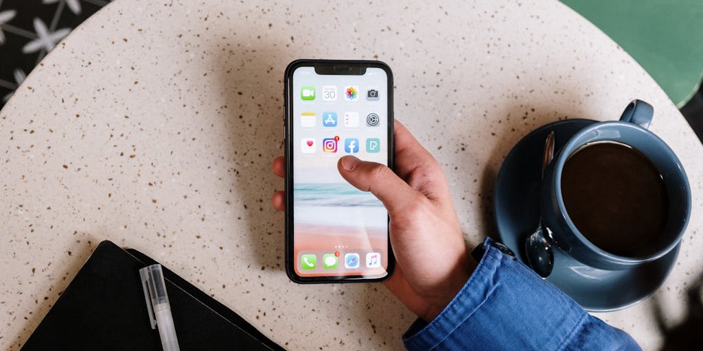 A creative flat lay of various social media icons and a smartphone displaying the Zoho Social app, with a notepad listing social media strategies. The arrangement emphasizes the integration of social media tools in modern marketing.