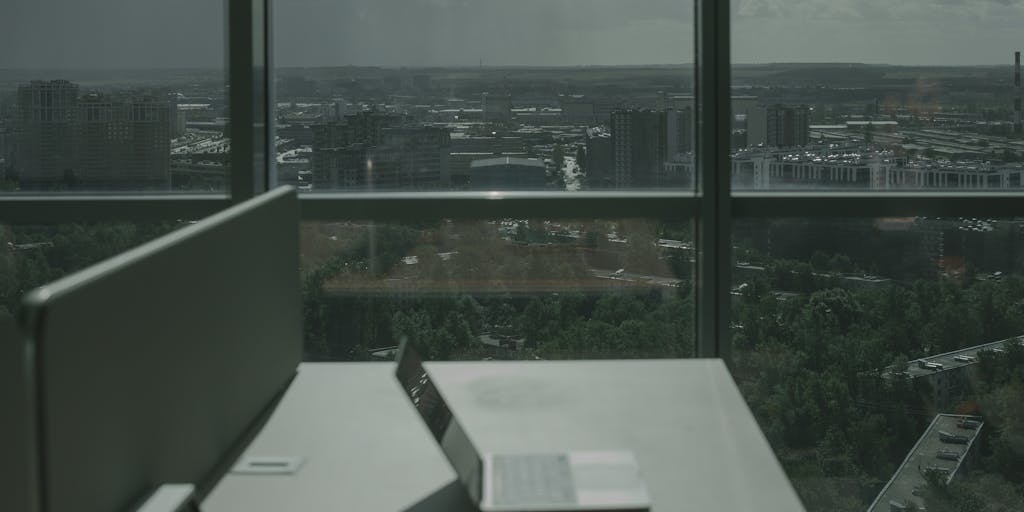 A vibrant workspace scene featuring a laptop open to the Vista Social dashboard, surrounded by colorful sticky notes and a coffee cup. The background includes a window with a view of a city skyline, symbolizing connectivity and social engagement.