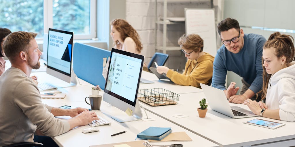 A vibrant workspace featuring a diverse group of people collaborating on social media strategies. The scene includes laptops, colorful sticky notes, and a large whiteboard filled with ideas. The atmosphere is energetic and creative, showcasing teamwork and innovation in a modern office setting.