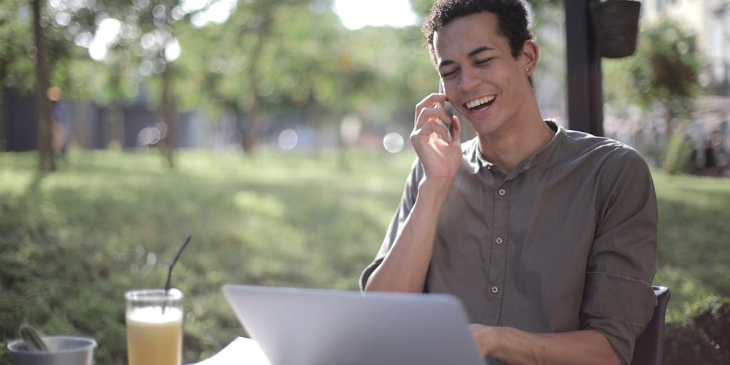 A dynamic action shot of a person enthusiastically using Vista Social on a laptop while another person is focused on their smartphone using Publer. Capture the energy and engagement of social media management in a lively environment, such as a café or co-working space.