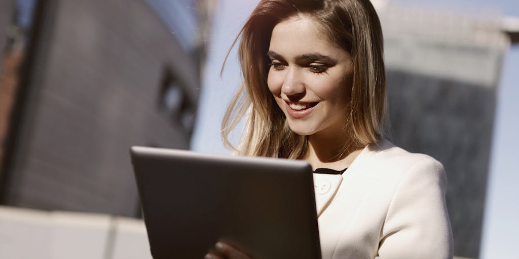 A dynamic action shot of a person engaging with both SocialPilot and Zoho Social on a tablet, with a thought bubble above their head showing pros and cons of each platform. The background can be a vibrant co-working space, filled with people collaborating, symbolizing the social aspect of social media management.