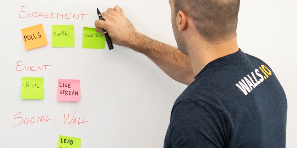 A dynamic action shot of a social media manager in a brainstorming session, with sticky notes and sketches on a whiteboard. One side of the board is dedicated to strategies using Vista Social, while the other side showcases ideas for SocialPilot. The manager is seen actively engaging with the board, illustrating the planning process for using both platforms.