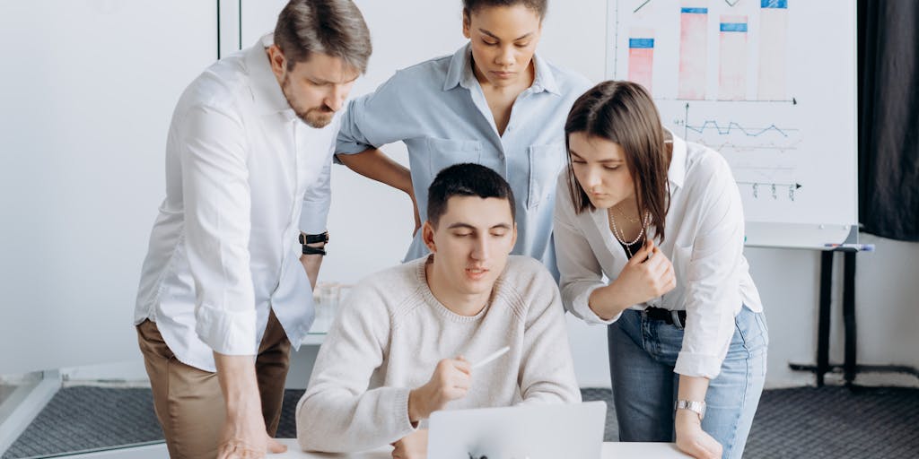 A split-screen image showcasing two digital marketing teams in action. On one side, a team using Metricool is analyzing data on a large screen filled with graphs and metrics, while on the other side, a Vista Social team is engaged in a brainstorming session with colorful sticky notes and social media icons around them. The contrasting environments highlight the different approaches to social media management.