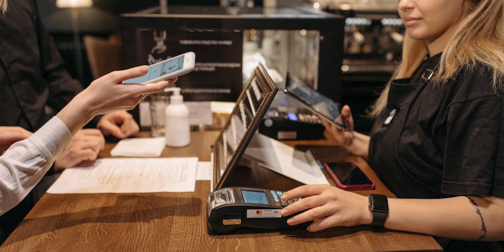 A dynamic action shot of a person engaging with both platforms on their devices. One hand is on a tablet displaying Zoho Social, while the other is on a smartphone showing Agorapulse. The background can be a lively coffee shop, illustrating the flexibility and mobility of managing social media on the go.