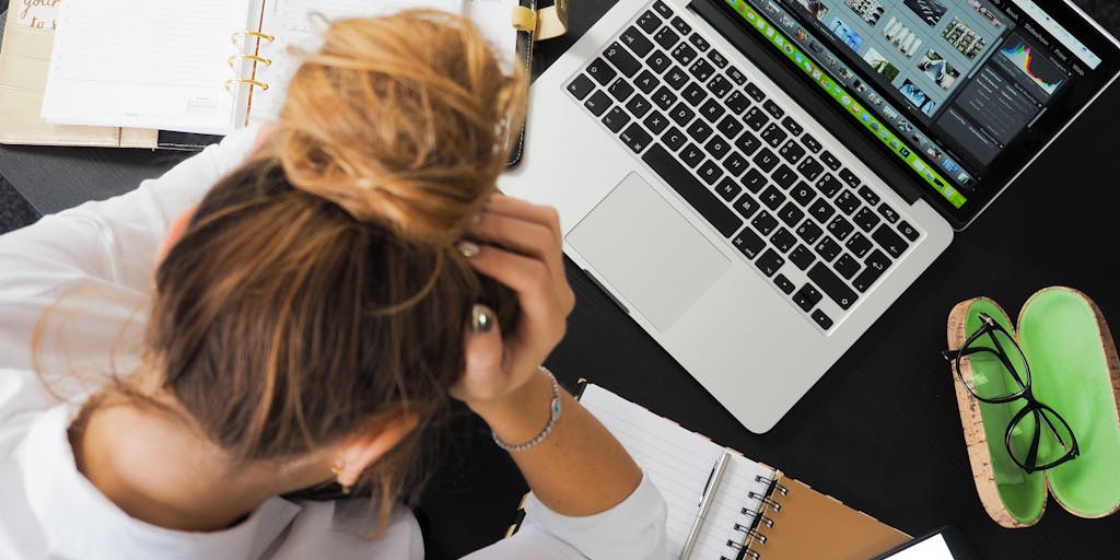 A split-screen image showing two desks side by side. On one side, a person is using SocialBee with a vibrant, colorful interface on their computer, surrounded by social media icons and engagement metrics. On the other side, a person is using Zoho Social with a more minimalist, professional setup, featuring charts and analytics. The contrasting environments highlight the different vibes of each platform.